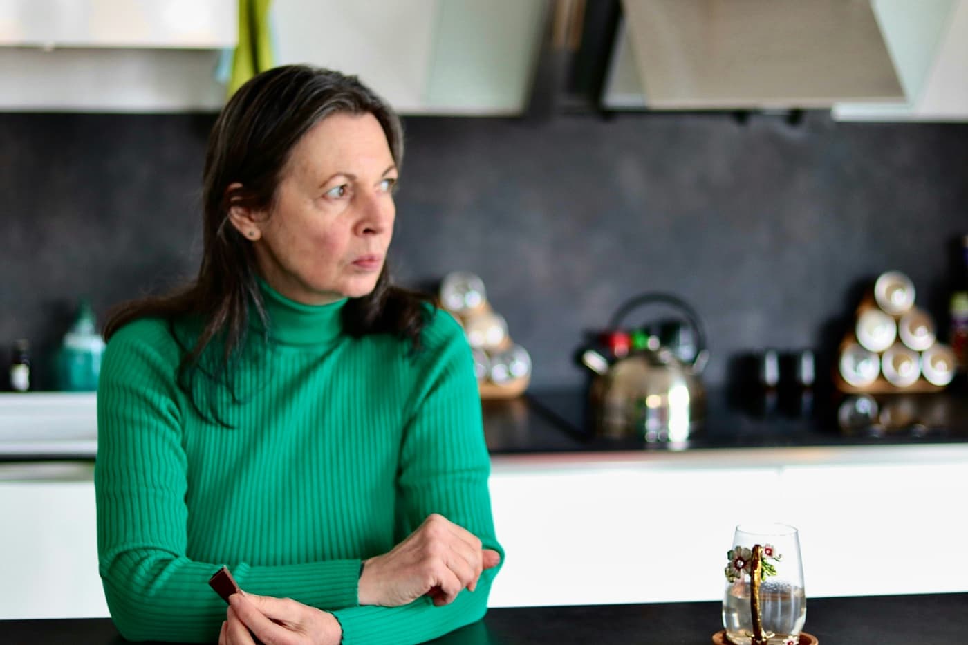 A parent at the kitchen counter, looking away in thought